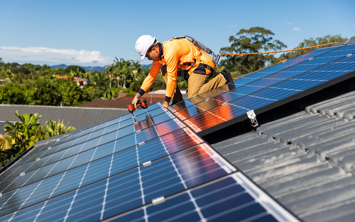 A contractor installs solar panels on a sunny roof.